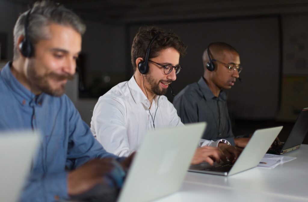 Três homens trabalhando com notebook e headset na operação de automação no service desk.