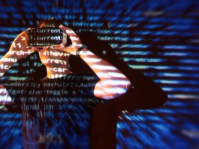 Double exposure of a caucasian man and Virtual reality VR headset is presumably a gamer or a hacker cracking the code into a secure network or server, with lines of code