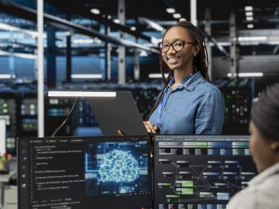 Happy specialist inspecting neural network data center used for machine learning. Portrait of smiling engineer doing maintenance on server hub to optimize it for artificial intelligence workloads.
