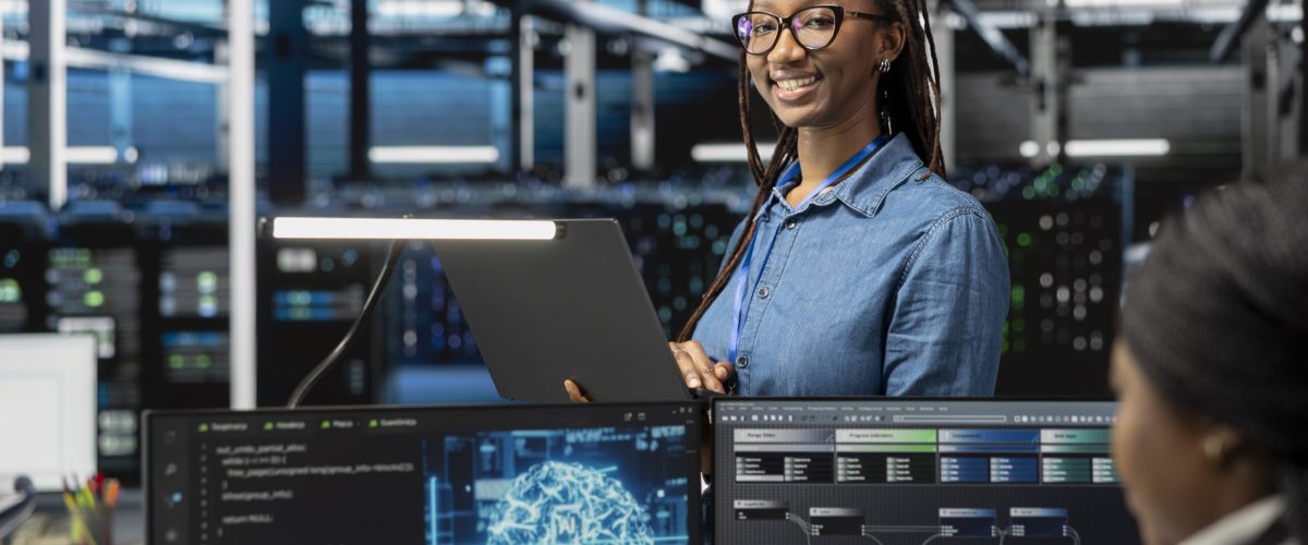 Happy specialist inspecting neural network data center used for machine learning. Portrait of smiling engineer doing maintenance on server hub to optimize it for artificial intelligence workloads.