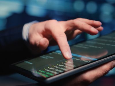 Male system administrator inspecting big data on tablet, working in modern data center. Infrastructure specialist inspecting server rack systems, artificial intelligence. Handheld shot. Close up.