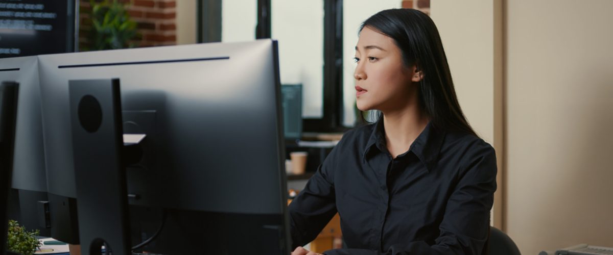 Portrait of asian programer focused on writing code sitting at desk in software development office. System engineer concentrating on creating algorithm for it startup company.