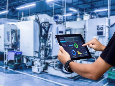 Smart industry control concept.Hands holding tablet on blurred automation machine as background