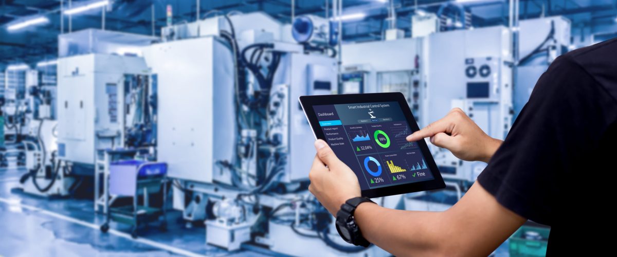 Smart industry control concept.Hands holding tablet on blurred automation machine as background