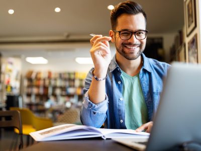 Smiling male student working and learning in a library