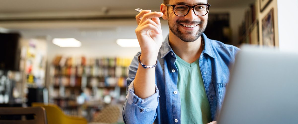 Smiling male student working and learning in a library