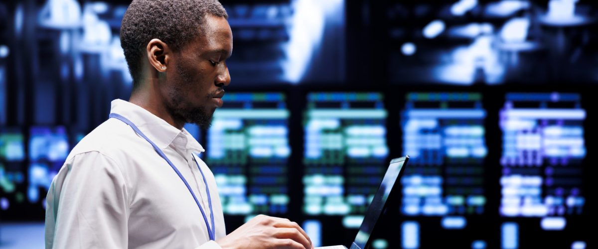 African american system administrator typing supercomputer hub contingency plan on laptop to provide fast restoration of service, limiting damage and minimizing interruptions to normal operations